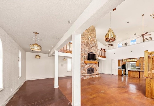 unfurnished living room with a fireplace, finished concrete floors, ceiling fan, a textured ceiling, and baseboards