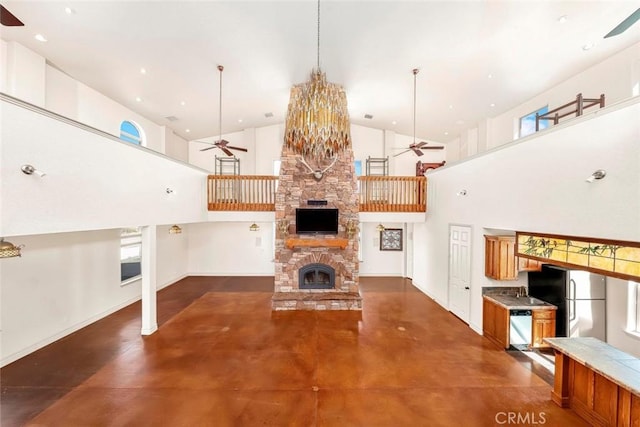 unfurnished living room featuring baseboards, a towering ceiling, ceiling fan, finished concrete floors, and a fireplace