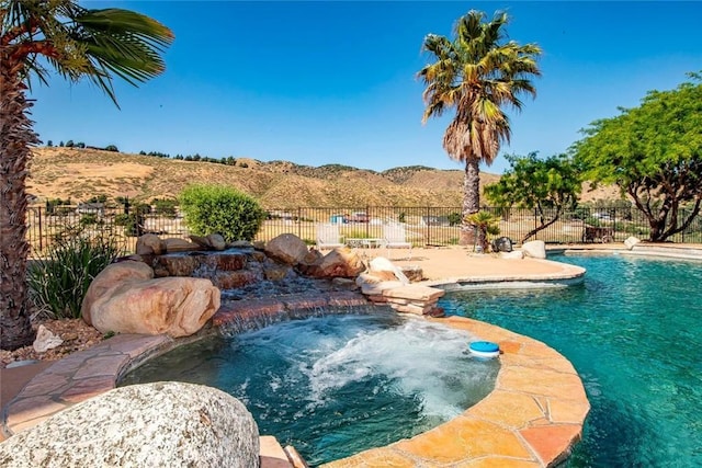 view of pool featuring a fenced in pool, a mountain view, fence, and an in ground hot tub