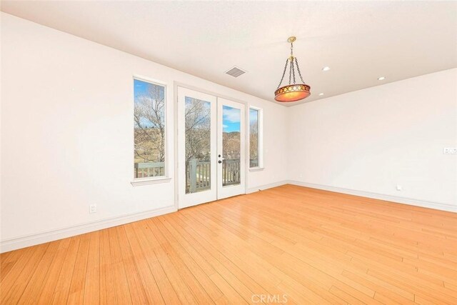 empty room with baseboards, french doors, visible vents, and light wood-style floors