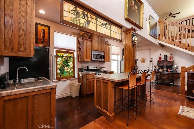 kitchen with appliances with stainless steel finishes, plenty of natural light, a sink, and brown cabinets