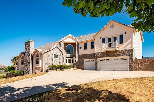 view of front of home with stone siding, a balcony, and concrete driveway