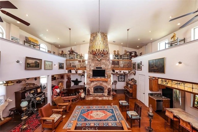 living room featuring ceiling fan, high vaulted ceiling, and a stone fireplace