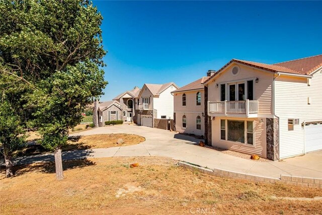 back of house featuring a garage, a residential view, driveway, and a balcony