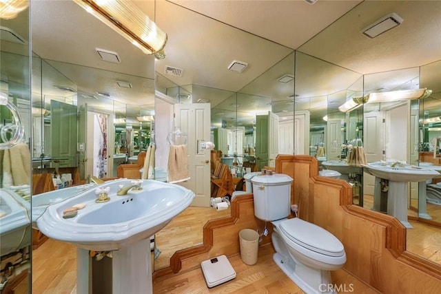 bathroom with toilet, visible vents, and wood finished floors