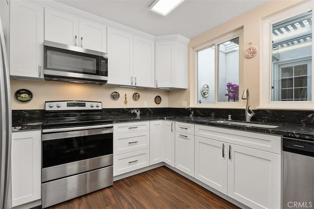 kitchen featuring white cabinetry, stainless steel appliances, dark stone counters, sink, and dark hardwood / wood-style floors