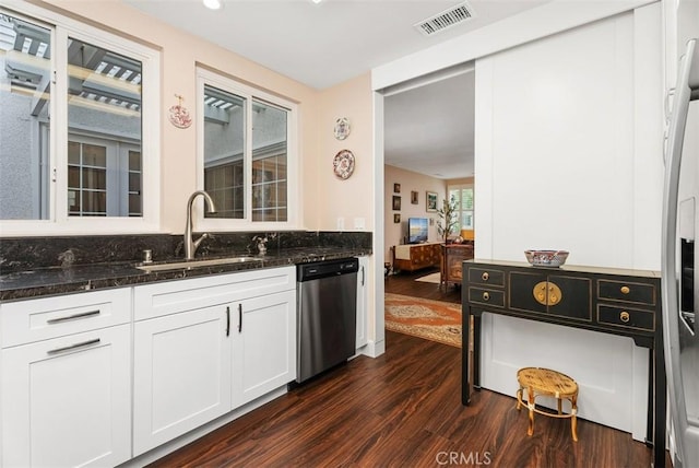 kitchen featuring dark stone countertops, stainless steel dishwasher, sink, white cabinetry, and dark wood-type flooring