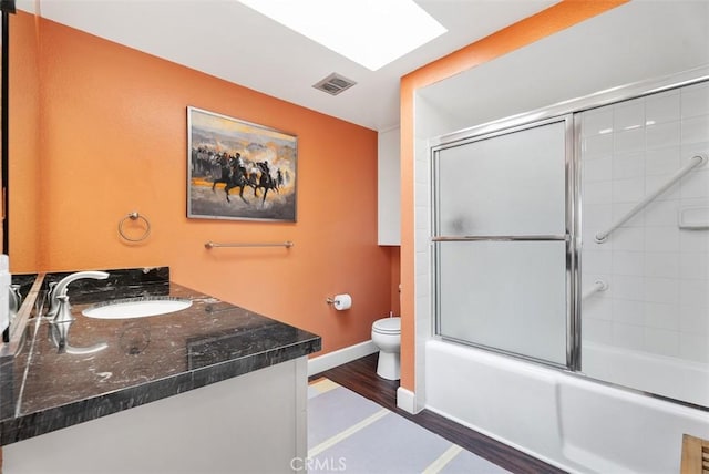 full bathroom with combined bath / shower with glass door, vanity, toilet, and hardwood / wood-style flooring