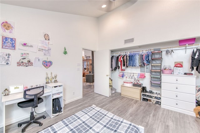 bedroom featuring light wood-type flooring, a closet, and a high ceiling