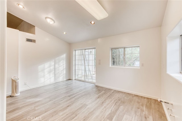 empty room with light wood-type flooring and vaulted ceiling