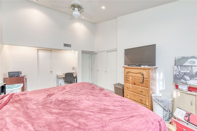 bedroom featuring ceiling fan, two closets, and a high ceiling