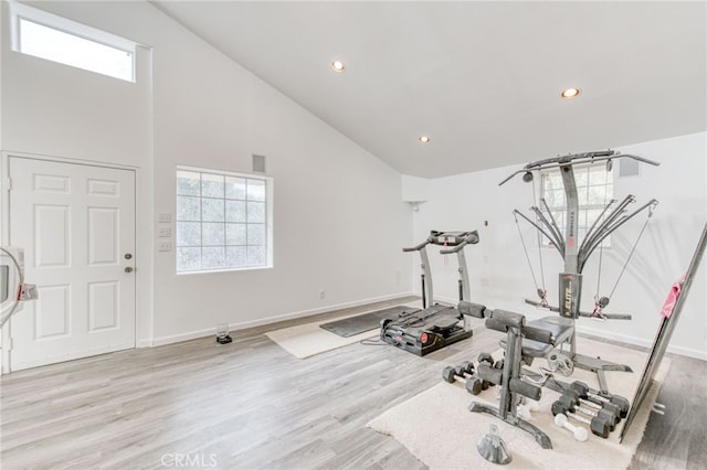 exercise area featuring light hardwood / wood-style flooring and high vaulted ceiling