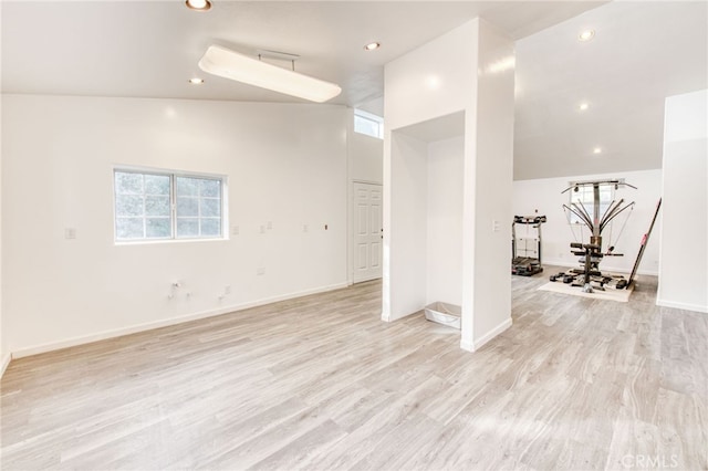 empty room with high vaulted ceiling and light hardwood / wood-style floors