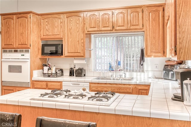 kitchen with tile counters, sink, and white appliances