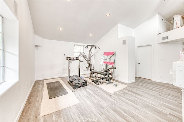 workout area with high vaulted ceiling and light hardwood / wood-style flooring