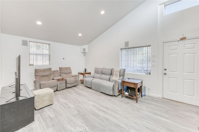 living room featuring high vaulted ceiling, plenty of natural light, and light hardwood / wood-style floors