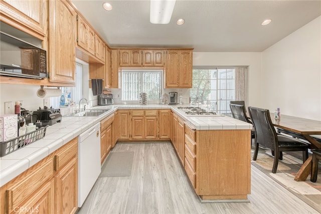 kitchen with tile counters, light wood-type flooring, sink, and white appliances