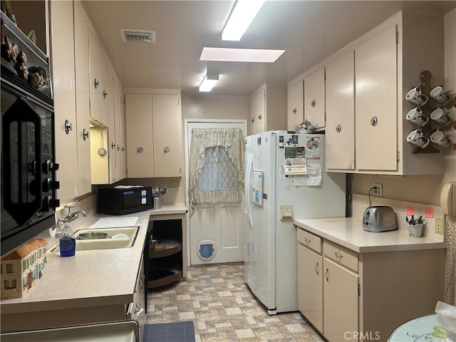 kitchen featuring white refrigerator with ice dispenser, a skylight, and sink