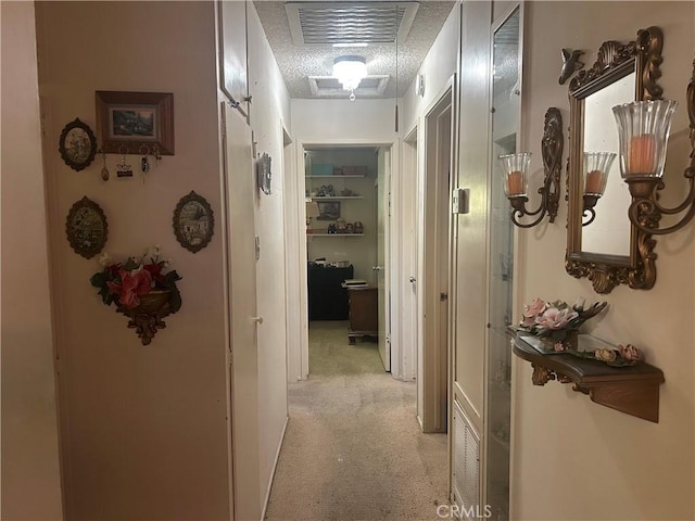 hallway with light colored carpet and a textured ceiling