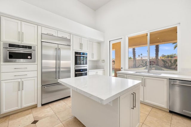 kitchen featuring white cabinets, a kitchen island, stainless steel appliances, sink, and light tile patterned floors