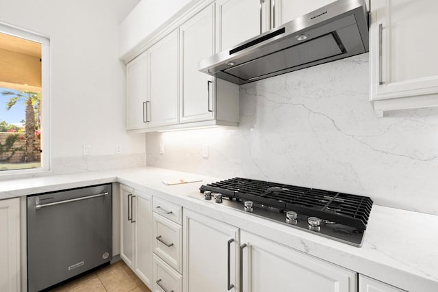 kitchen featuring backsplash, stainless steel dishwasher, white cabinetry, light stone countertops, and gas stovetop