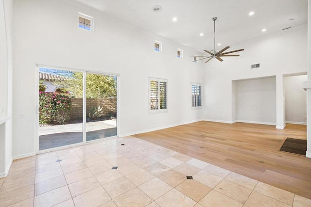 unfurnished living room with ceiling fan, a high ceiling, and light tile patterned floors