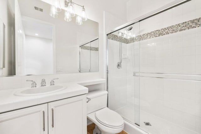 bathroom with an enclosed shower, vanity, and toilet