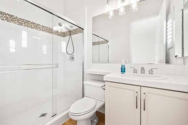 bathroom featuring toilet, vanity, and an enclosed shower