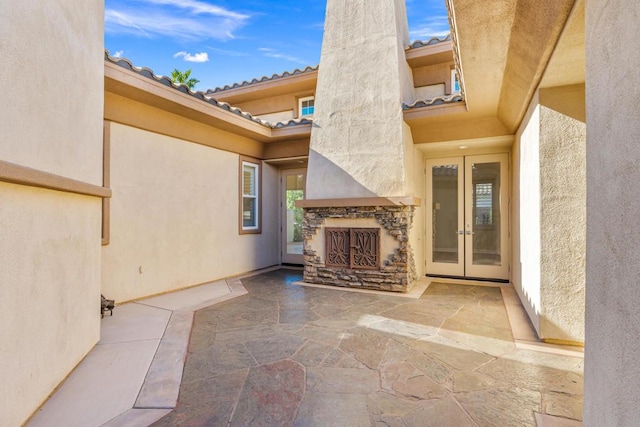 view of patio with french doors and an outdoor stone fireplace