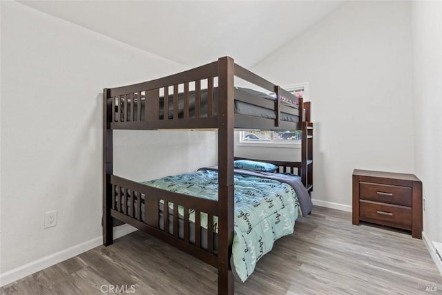 bedroom with lofted ceiling, wood finished floors, and baseboards