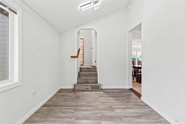 interior space featuring baseboards, wood finished floors, stairs, and vaulted ceiling