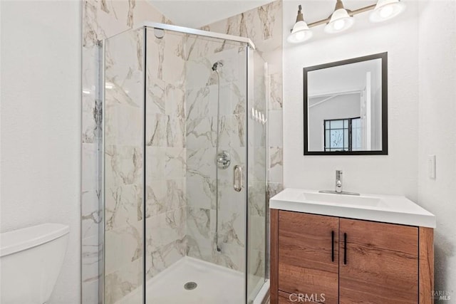 full bath featuring a marble finish shower, toilet, and vanity