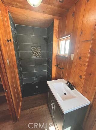 bathroom featuring wood ceiling, wood walls, and tiled shower