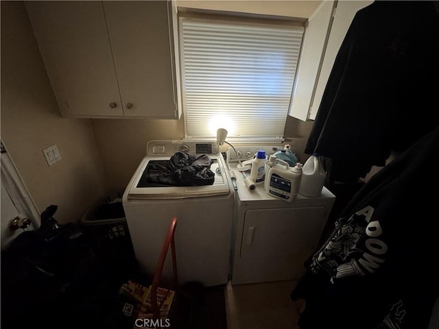 clothes washing area featuring separate washer and dryer and cabinets