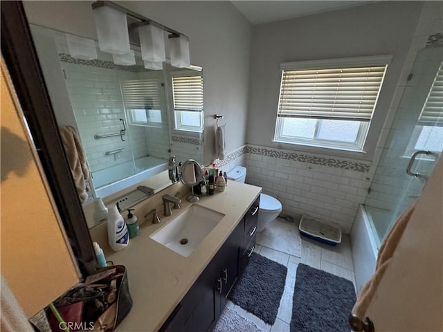 full bathroom featuring vanity, tile walls, shower / bath combination with glass door, and toilet