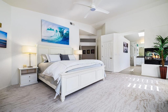 carpeted bedroom with ensuite bathroom, ceiling fan, and vaulted ceiling