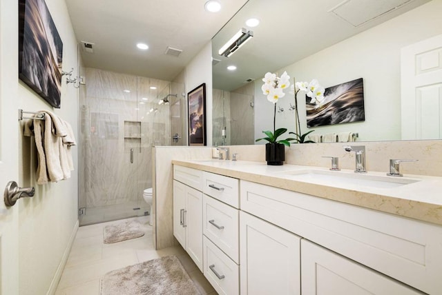 bathroom with a shower with shower door, vanity, tile patterned floors, and toilet