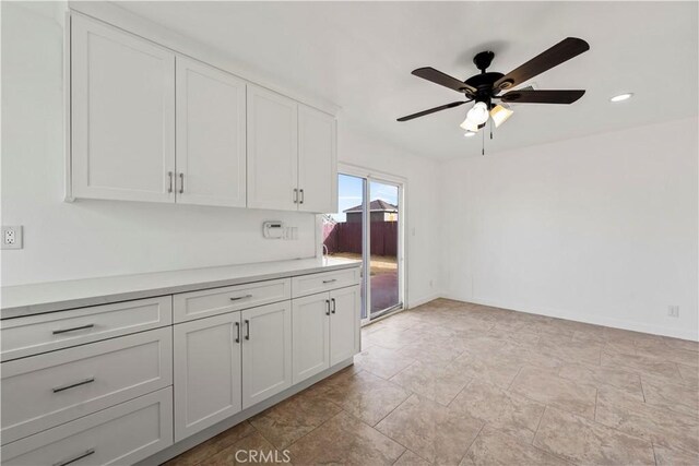 kitchen featuring ceiling fan and white cabinets