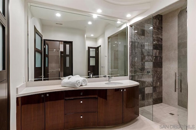 bathroom with tile patterned flooring, a shower with shower door, and vanity