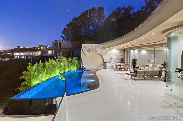 pool at dusk featuring a patio area and an outdoor living space