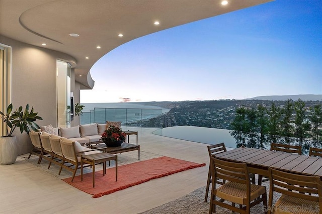 balcony at dusk featuring an outdoor living space, a water view, and a patio