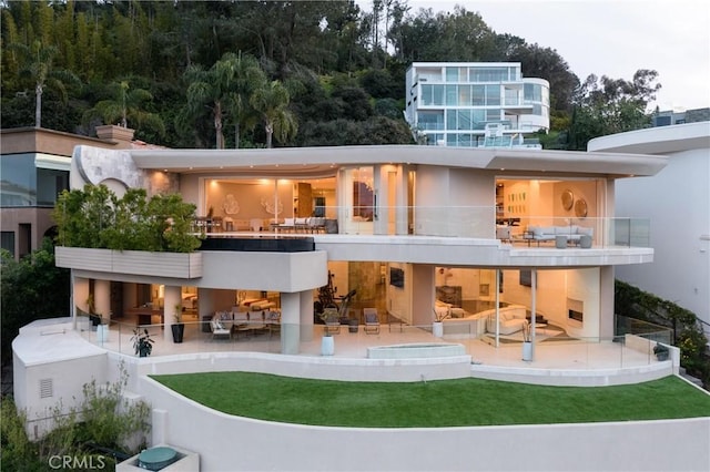 back of property featuring a balcony, a patio area, an outdoor bar, a yard, and an outdoor living space