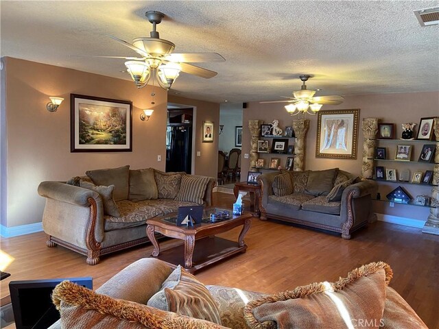 living area featuring visible vents, ceiling fan, and wood finished floors