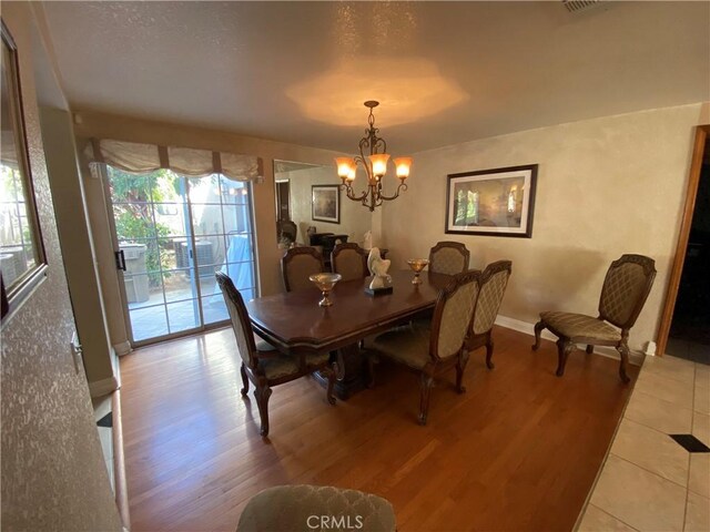 dining space with baseboards, light wood finished floors, and an inviting chandelier