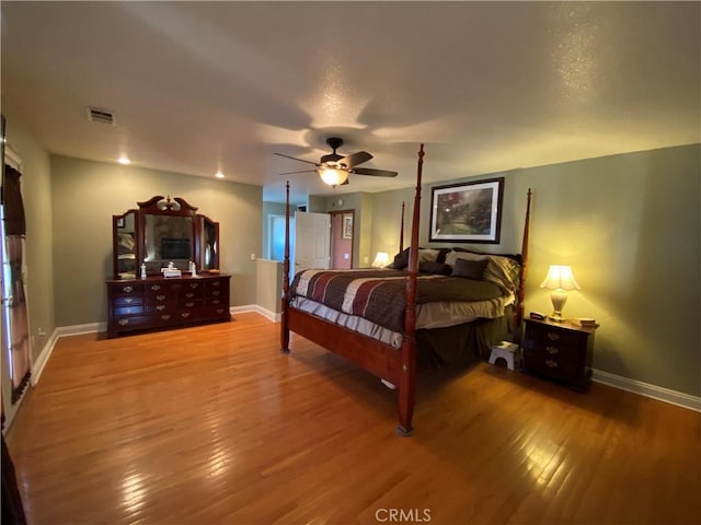 bedroom with wood finished floors, visible vents, and baseboards