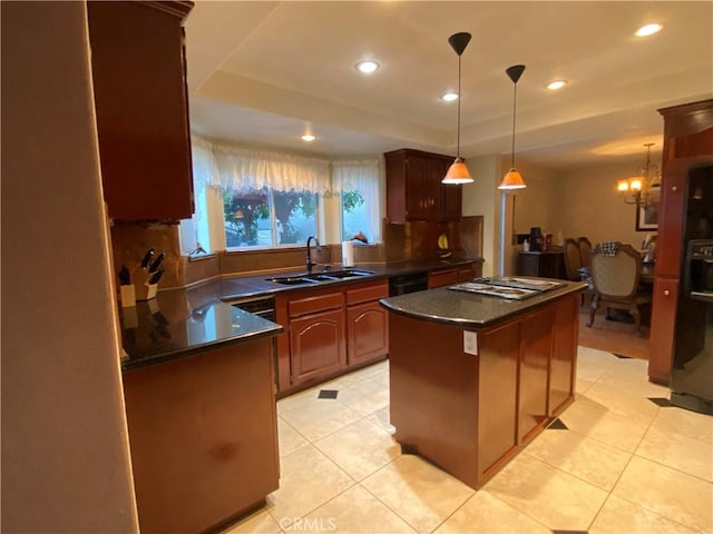 kitchen featuring a raised ceiling, dark countertops, a kitchen island, stainless steel stovetop, and a sink