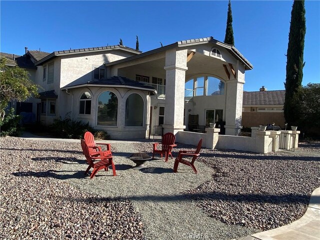 rear view of house with a fire pit and a patio