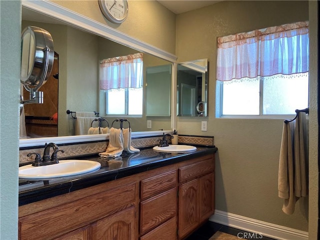 bathroom featuring double vanity, baseboards, and a sink