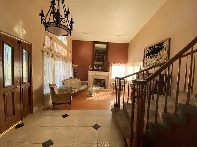 living area with light tile patterned floors, stairway, a tile fireplace, and visible vents