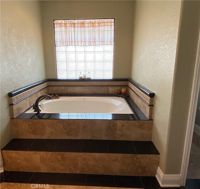 bathroom featuring a textured wall, a bath, and tile patterned floors